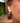 Close-up picture of long gold statement earrings Zia in burgundy worn by a model. Close-up foto van lange gouden oorbellen Zia in bordeaux gedragen door een model.
