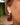 Close-up picture of long gold statement earrings Zia in burgundy worn by a model. Close-up foto van lange gouden oorbellen Zia in bordeaux gedragen door een model.