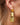 Close-up picture of Celeste: champagne colored gold long statement earrings worn on a model. Close-up foto van Celeste: champagnekleurige gouden lange oorbellen gedragen door een model.