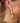 Close-up picture of Celeste: champagne colored gold long statement earrings worn on a model. Close-up foto van Celeste: champagnekleurige gouden lange oorbellen gedragen door een model.